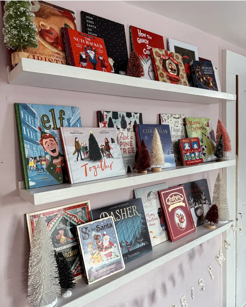 Some of the best Christmas picture books for kids including Elf, Together, Reindeer Express, Rudolph, Pick a Pine Tree, Night Before Christmas, and so much more. Picture books displayed on open shelves in a little girl's room.