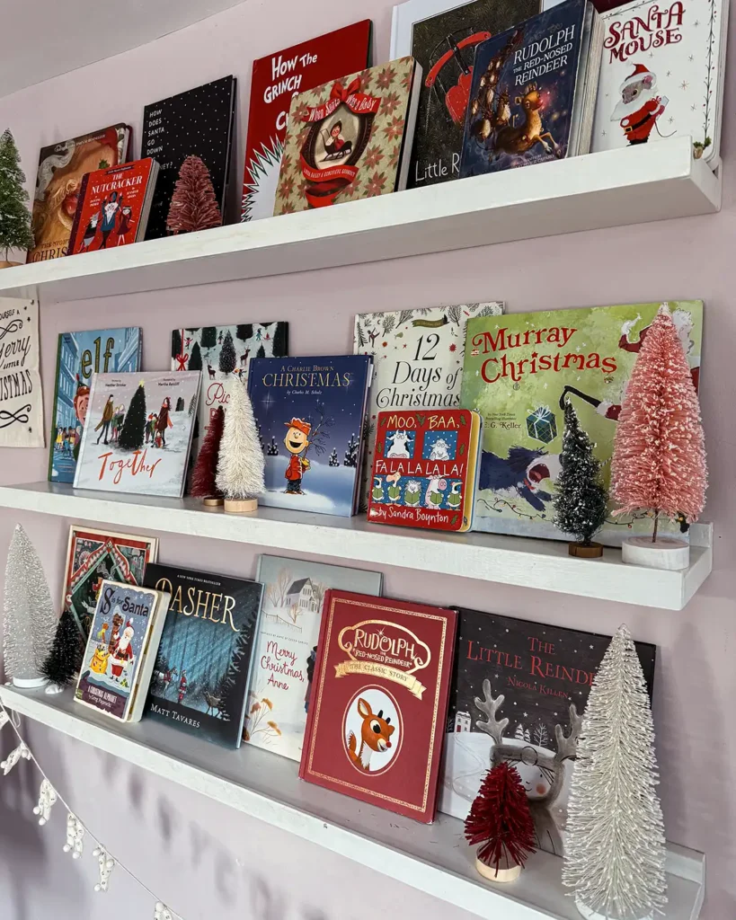 Children's Christmas picture books displayed on open shelves and decorated for Christmas with bottle brush trees and Christmas banner