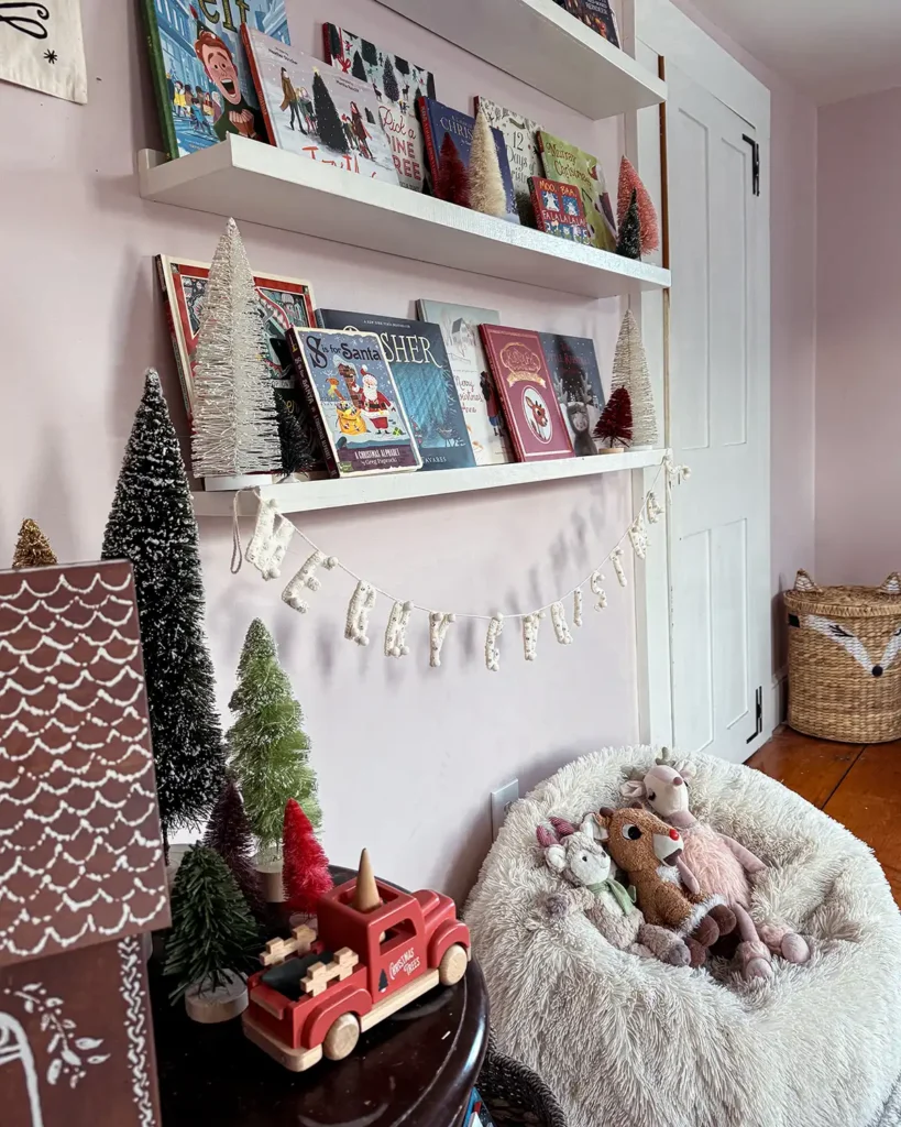 A fluffy white bean bag in a children's room with stuffed reindeer in front of a collection of Christmas picture books on open shelves for a cozy reading nook