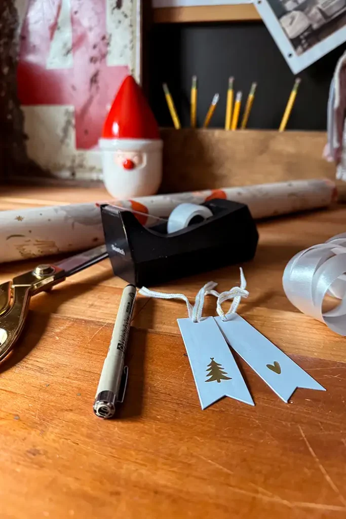 Featured image for gift wrapping essentials including wrapping paper rolls, tape, gift tags, ribbon, scissors, and pens