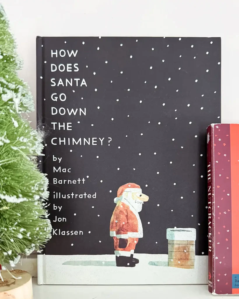 How Does Santa Go Down The Chimney? Christmas picture book sitting on an open bookshelf decorated with colorful bottle brush trees