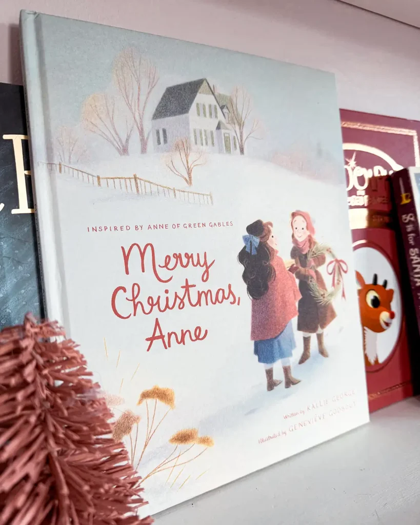 Merry Christmas Anne picture book sitting on a Christmas picture book bookshelf decorated for Christmas with colorful bottle brush trees