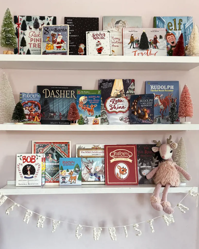 Kids bookshelves in a bedroom filled with Christmas books including a collection of reindeer picture books like Rudolph, Dasher, Reindeer Express and more