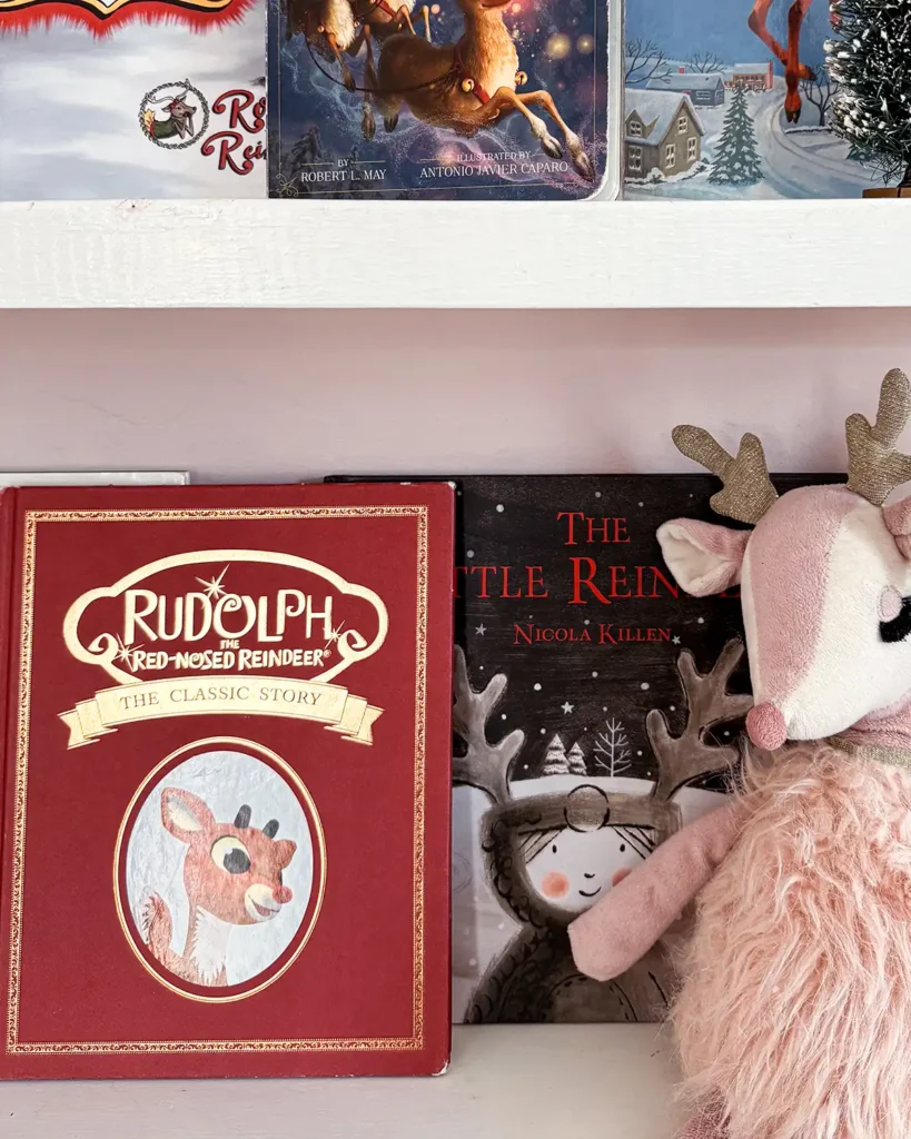 Rudolph the Red-Nosed Reindeer classic story picture book on open shelves with a pink reindeer stuffed animal