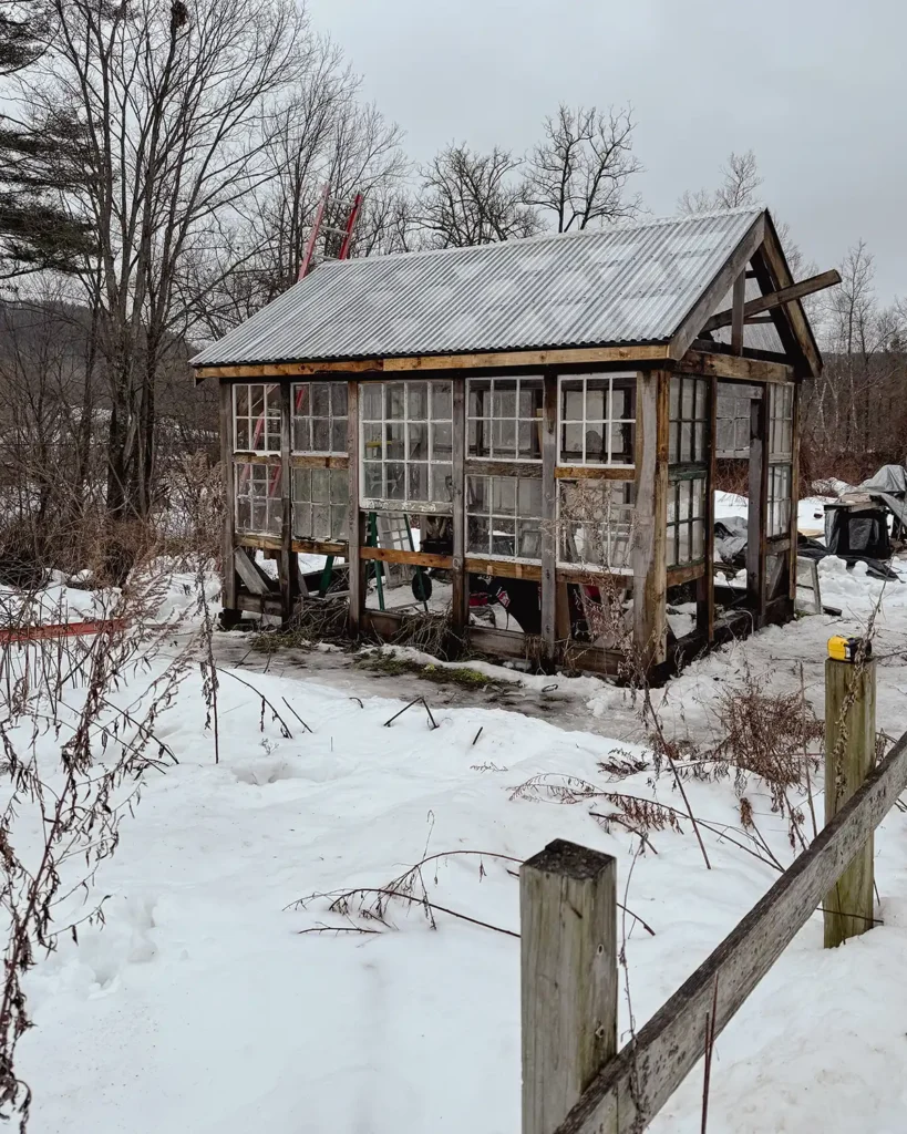 Greenhouse progress with the roof installed and most of the window sash installed on the sides