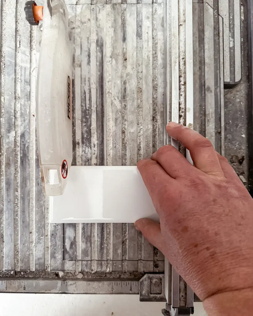 Tile saw cutting a white subway tile