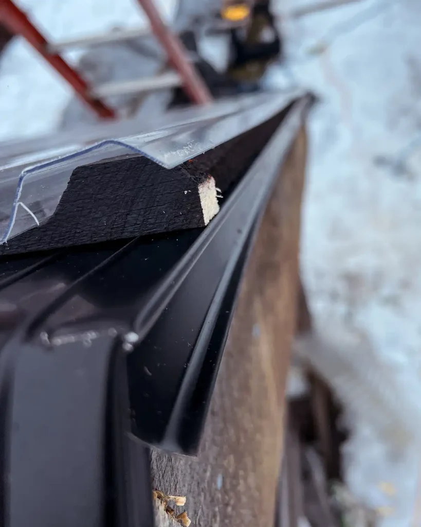 Lining up the first corrugated roofing panel with the closure strips