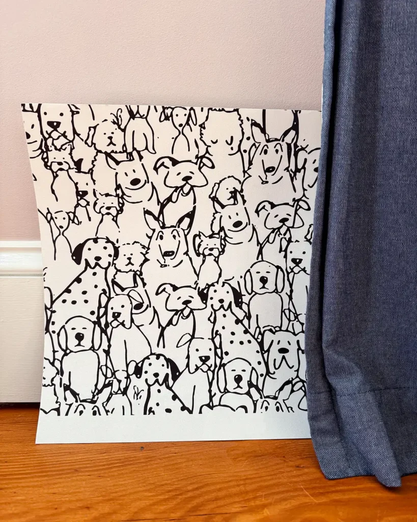 Black and white dog wallpaper sample from spoonflower propped up against a wall in a girls pink bedroom