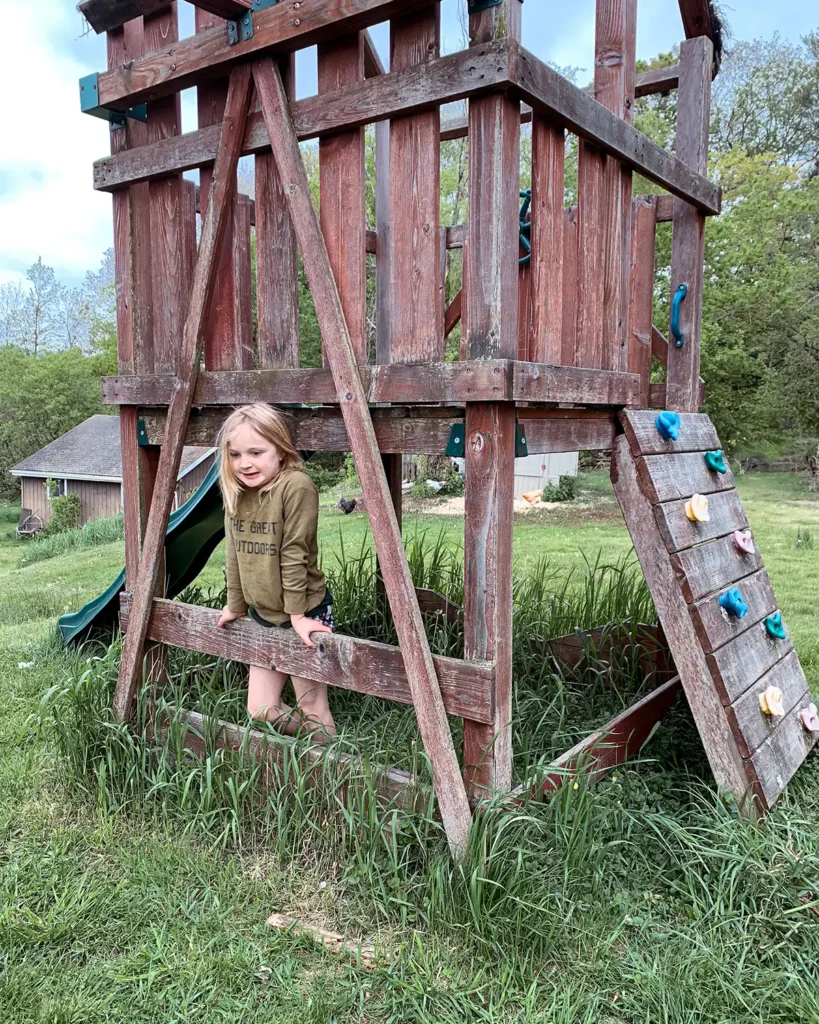 Old playground with weathered wood and a rock wall leading up to the second level of the structure