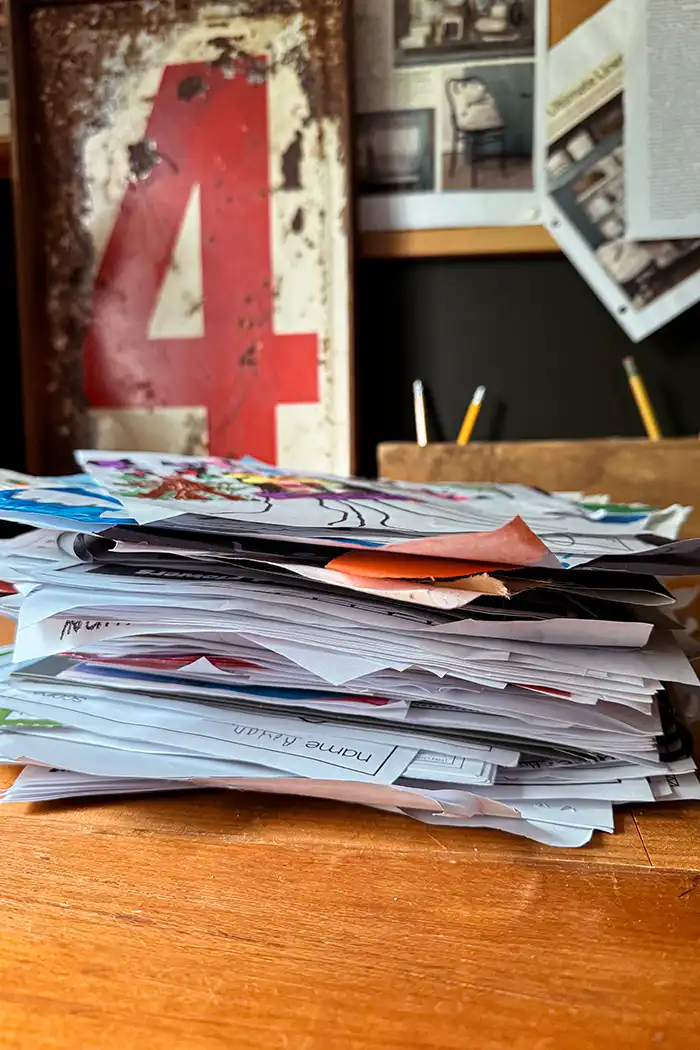 Storage ideas for kids school papers with stack of kids worksheets, artwork, newsletters, and more on a desk