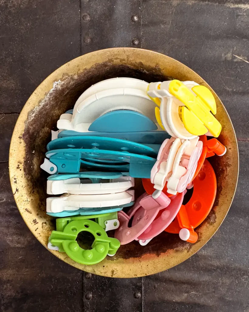 A collection of different styles of pom pom makers in a vintage brass bowl