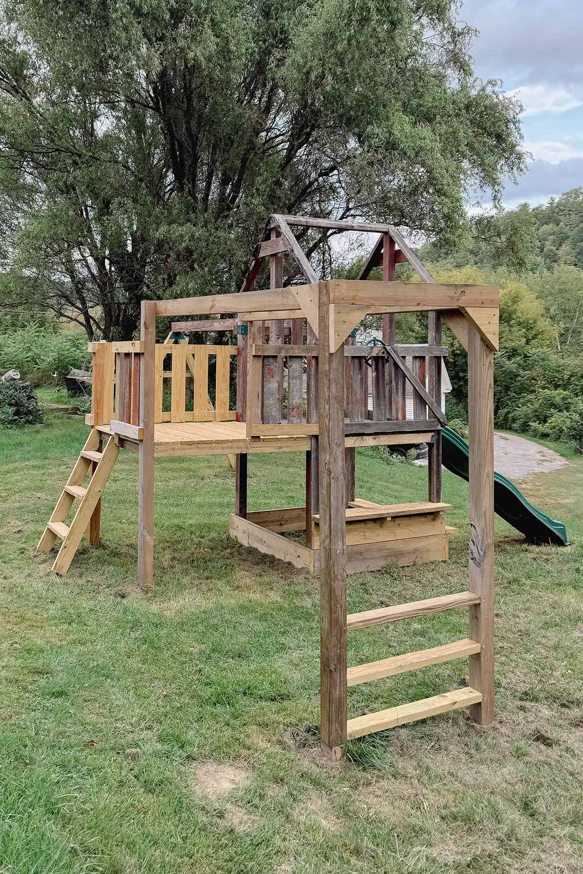 Playground renovation progress with monkey bars, extended deck, and sand box. Raw wood prepped for painting