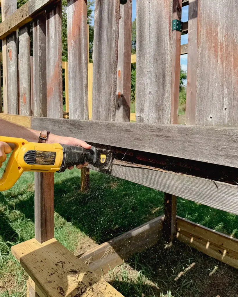 Using a Dewalt reciprocating saw to cut out a support beam from a playground structure