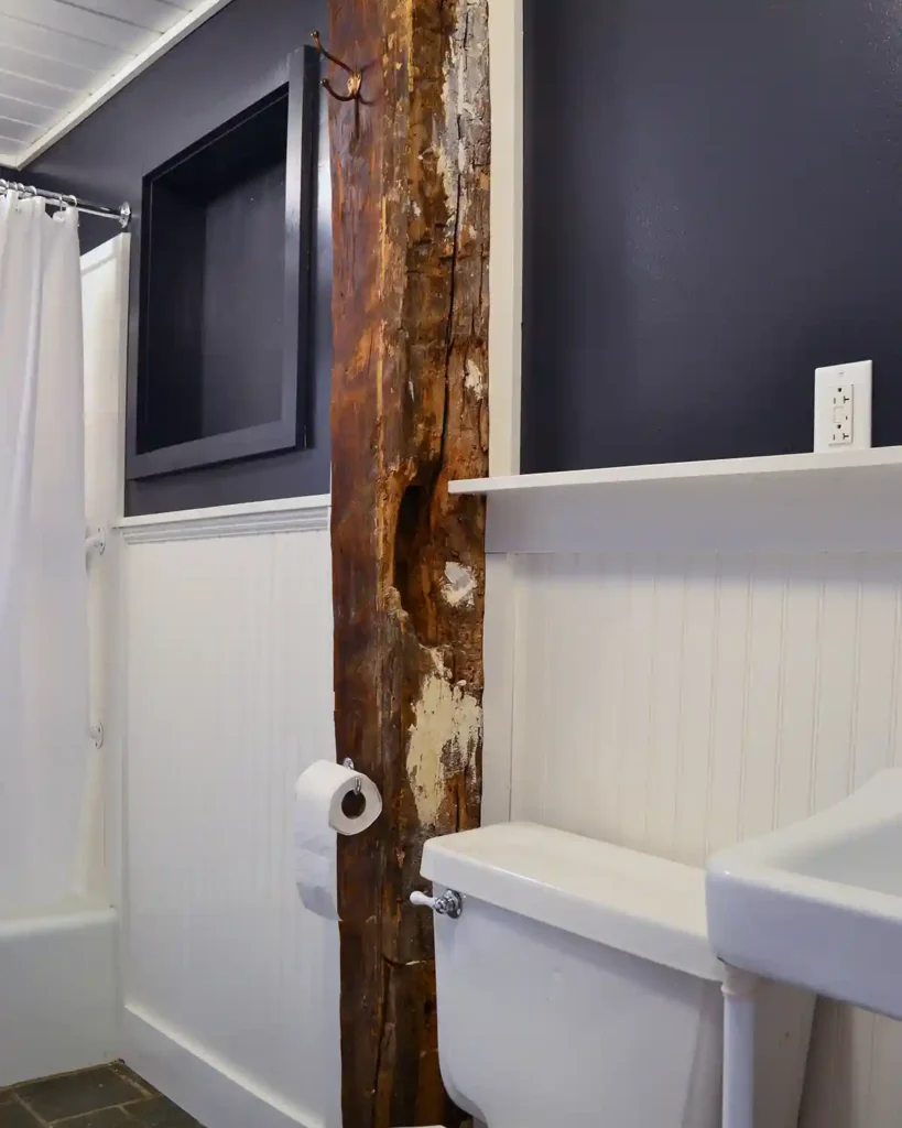 Bathroom reno progress with white beadboard installed on the lower half of the walls with a dark blue paint on the top half