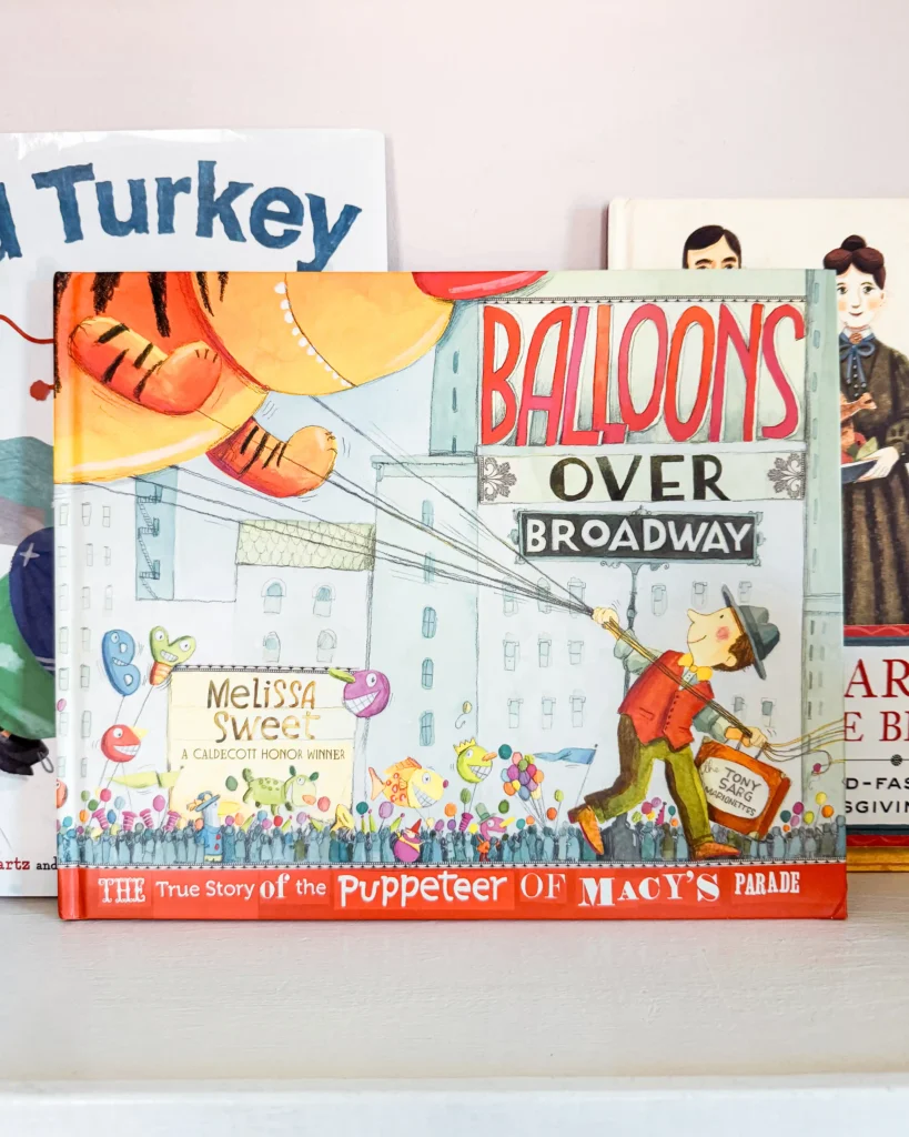 The "Balloons Over Broadway: The True Story Of The Puppeteer Of Macy's Parade" picture book sitting on a child's bookshelf