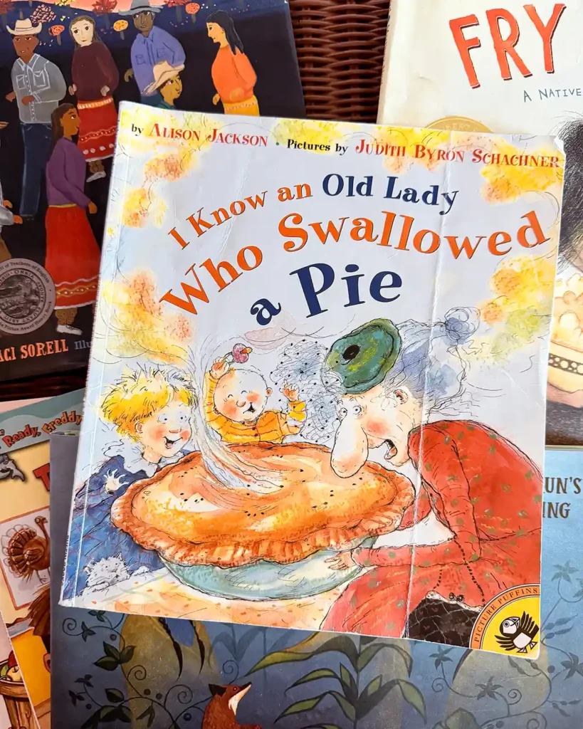 I Know An Old Lady Who Swallowed A Pie kids picture book sitting on top of a pile of Thanksgiving themed books on a kids' desk
