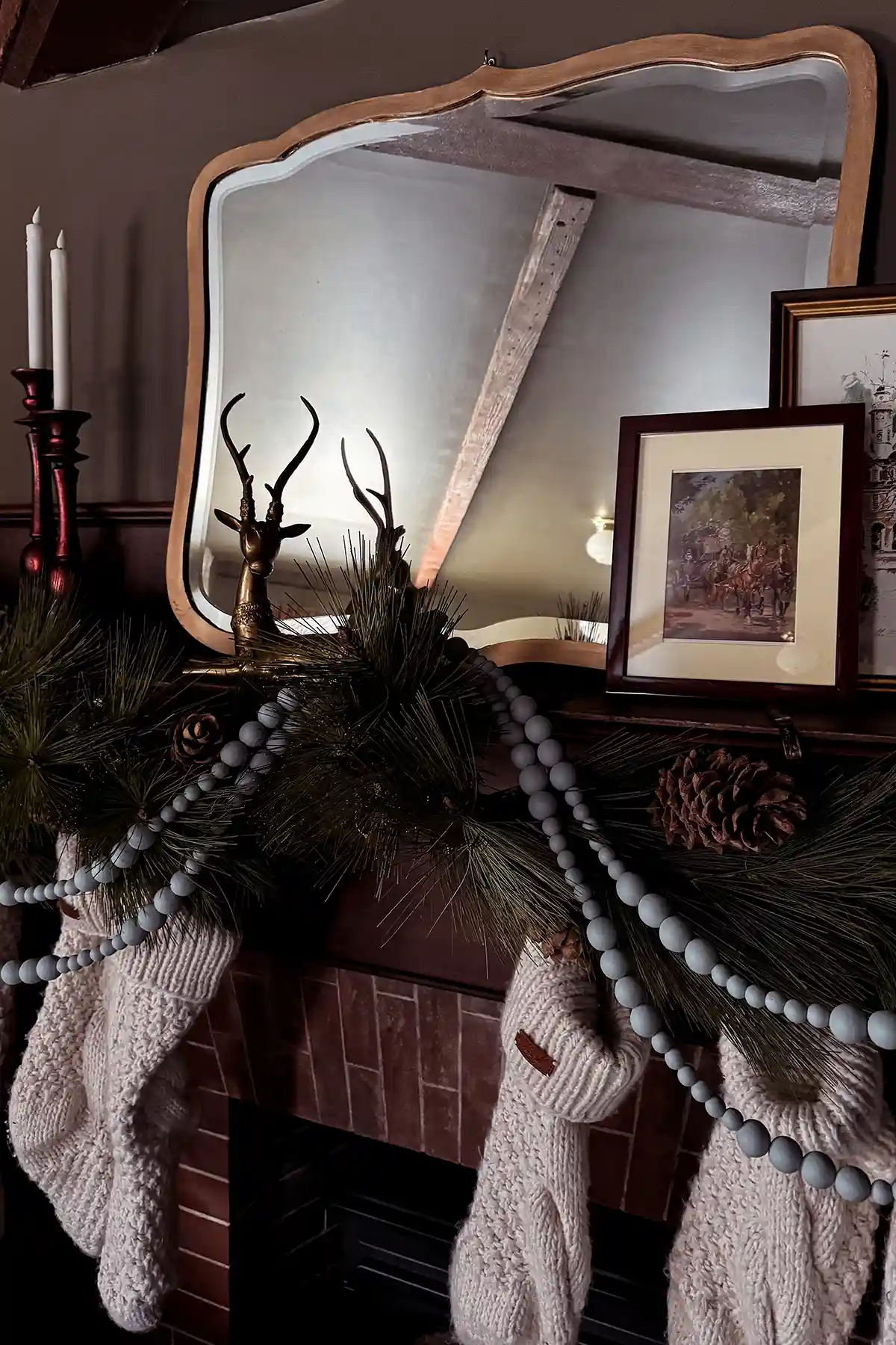 Holiday home tour 2024 featured image with a fireplace mantle decorated for Christmas with pine garlands, white knit stockings, light blue beaded garlands, gilded mirror, and red candlesticks