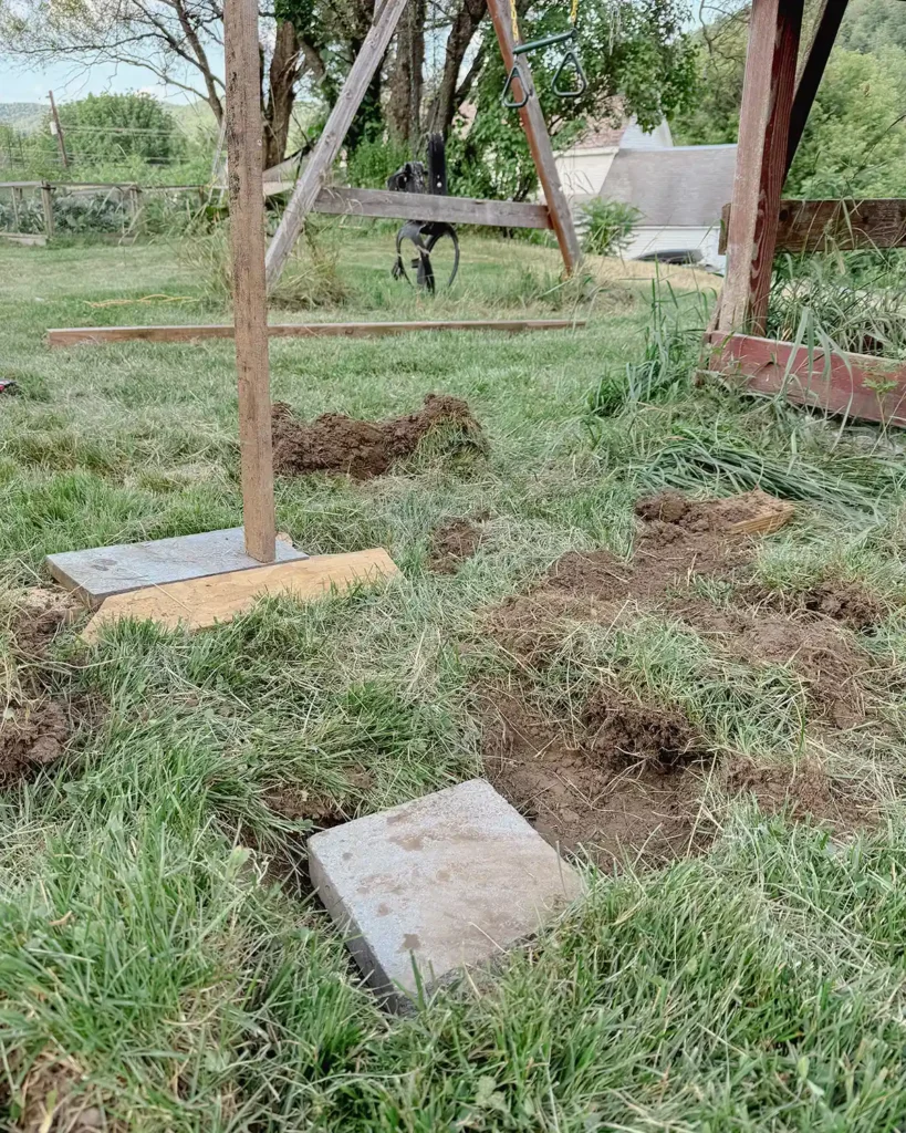 Digging a hole and inserting a cement block to serve as a cement footer for the DIY playground deck posts