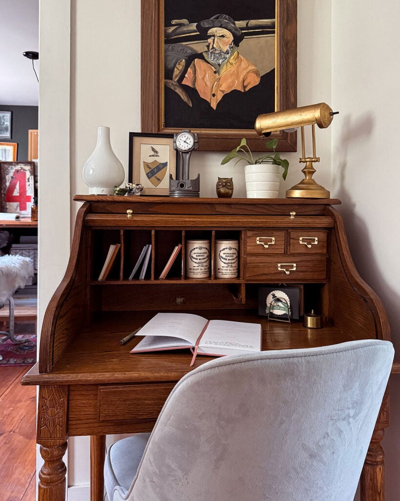 A refinished task lamp in Rub N Buff gold leaf sitting atop a small roll top desk with a notebook on it