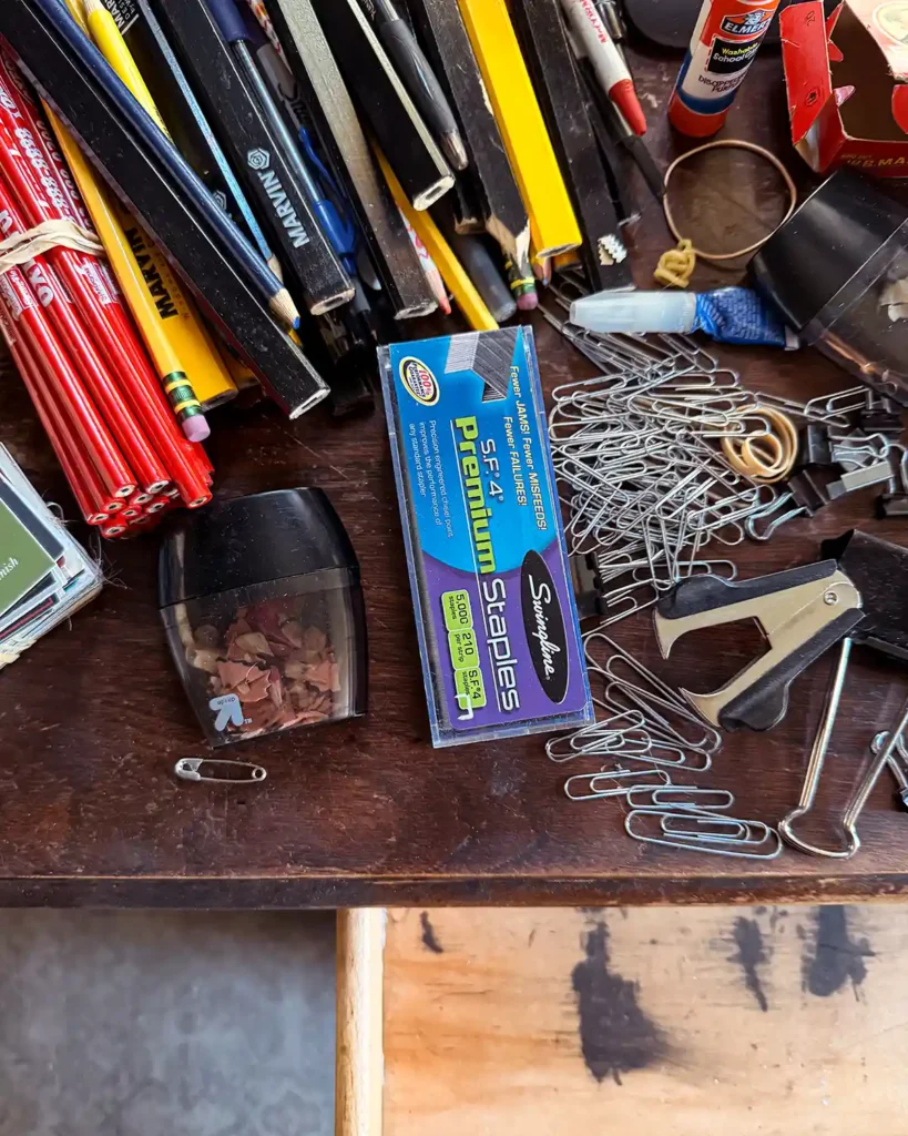 Piles of office supplies after cleaning out and decluttering a top desk drawer in a home office