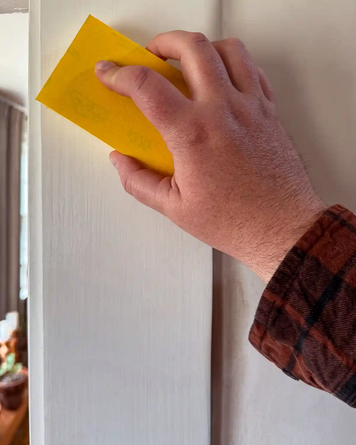 Sanding door trim before painting and between coats of paint using a yellow sanding block