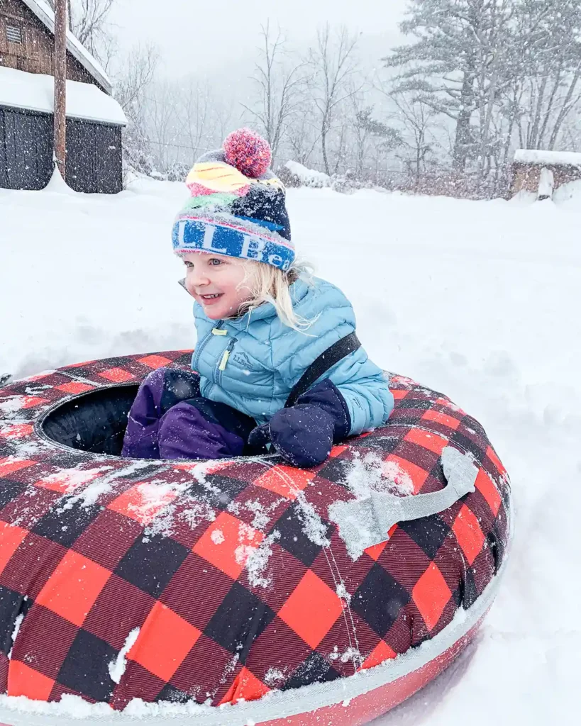 Sledding and tubing in the backyard during a snowstorm using a red and black plaid LL Bean snow tube
