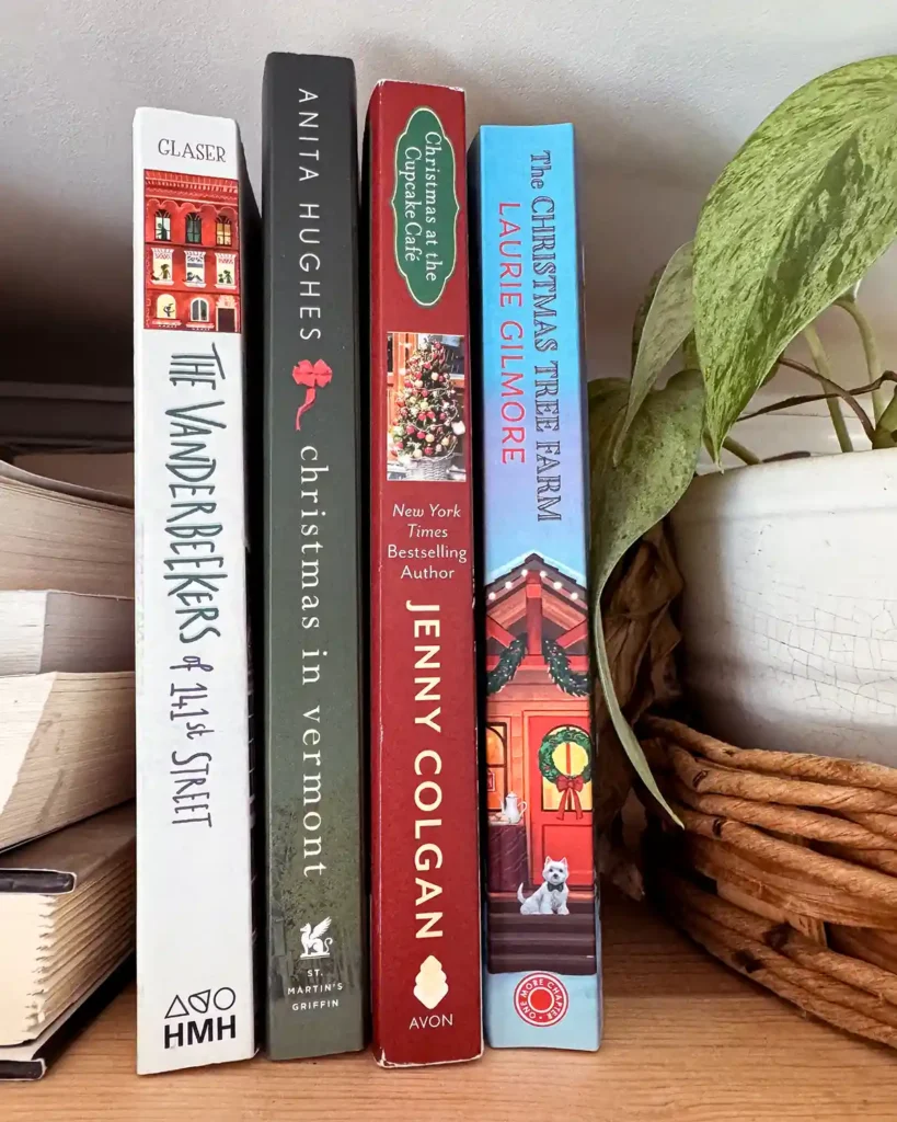 Christmas-themed fiction books sitting on a shelf including The Vanderbeekers of 141st Street by Karina Yan Glaser, Christmas in Vermont by Anita Hughes, Christmas at the Cupcake Cafe by Jenny Colgan, and The Christmas Tree Farm by Laurie Gilmore