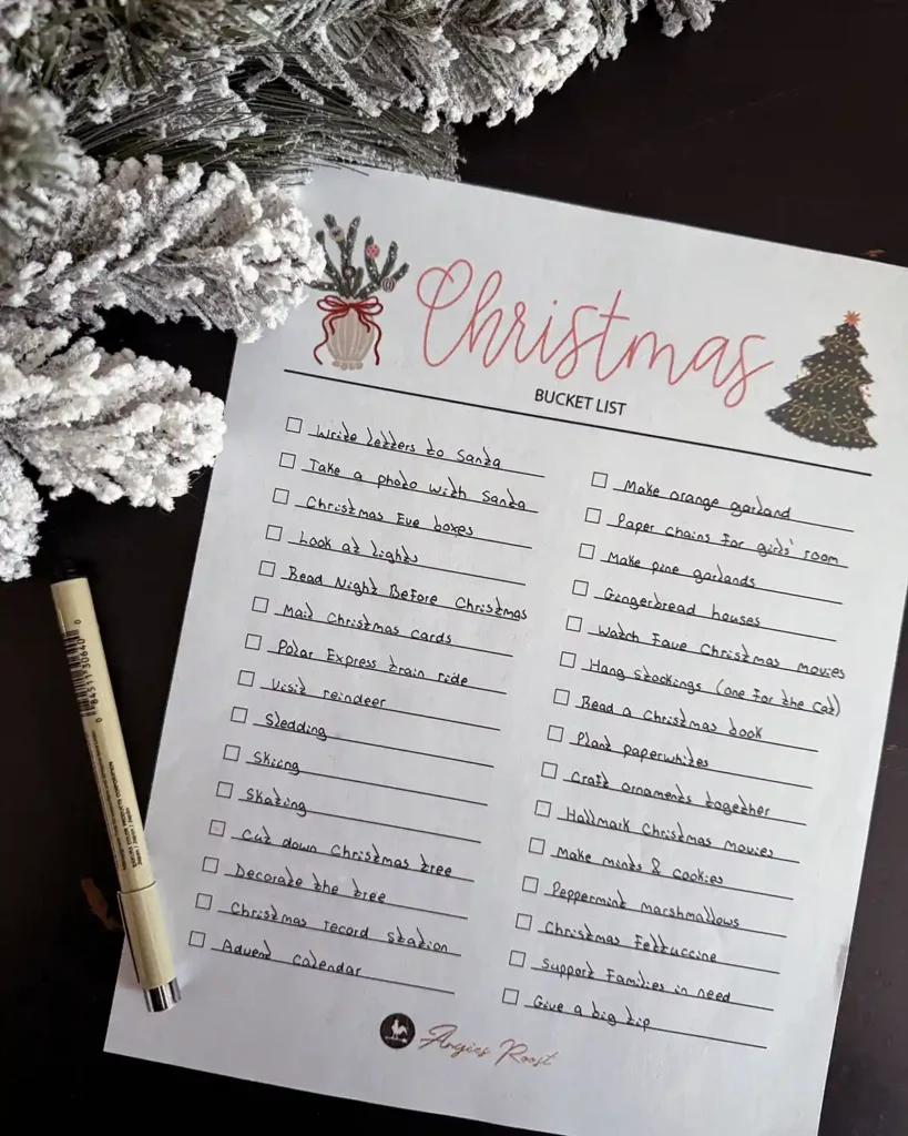 A Christmas bucket list printable checklist filled in with all the activities our family wants to try during the Christmas season; list sitting next to Christmas garland and a pen