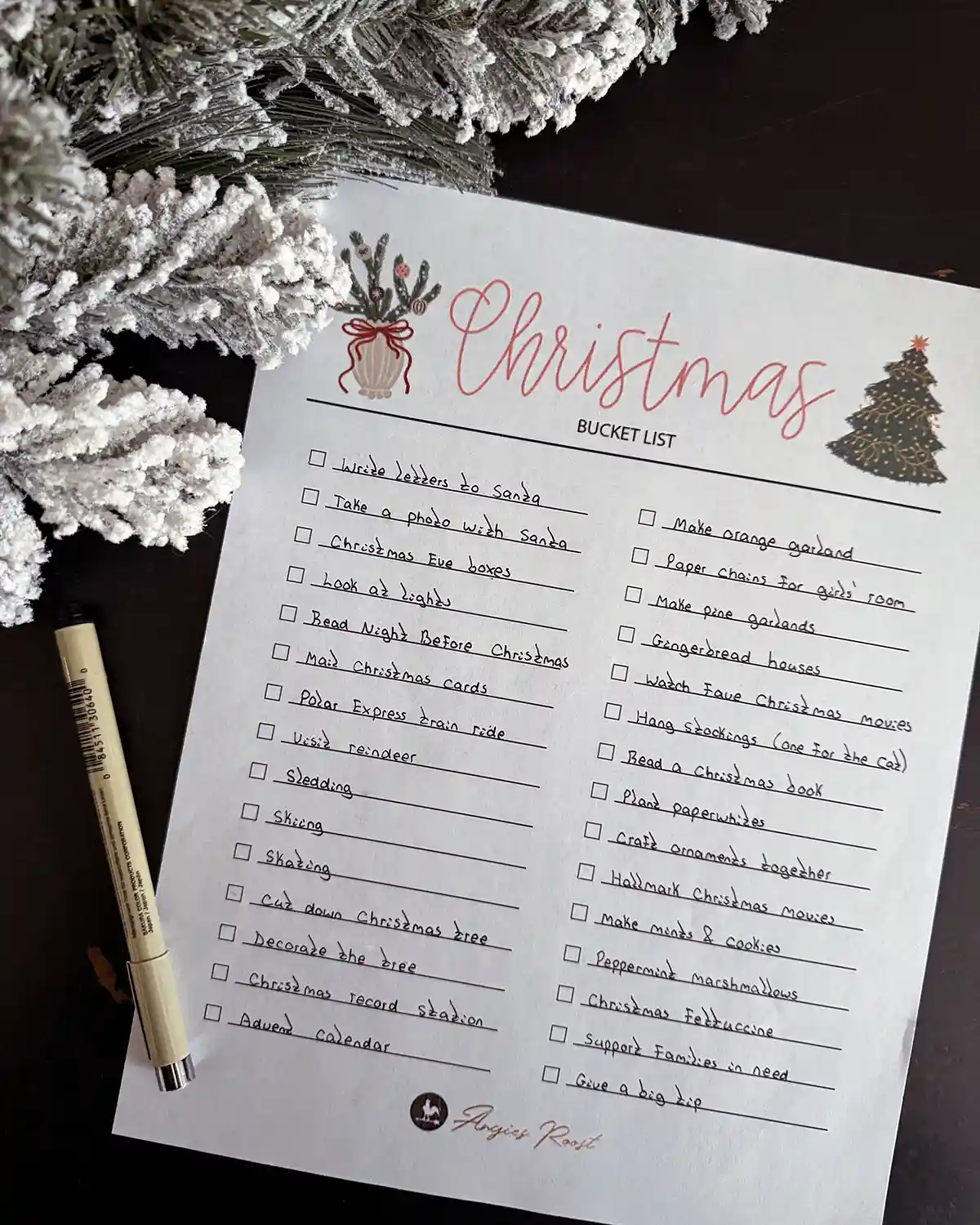 A Christmas bucket list printable checklist filled in with all the activities our family wants to try during the Christmas season; list sitting next to Christmas garland and a pen