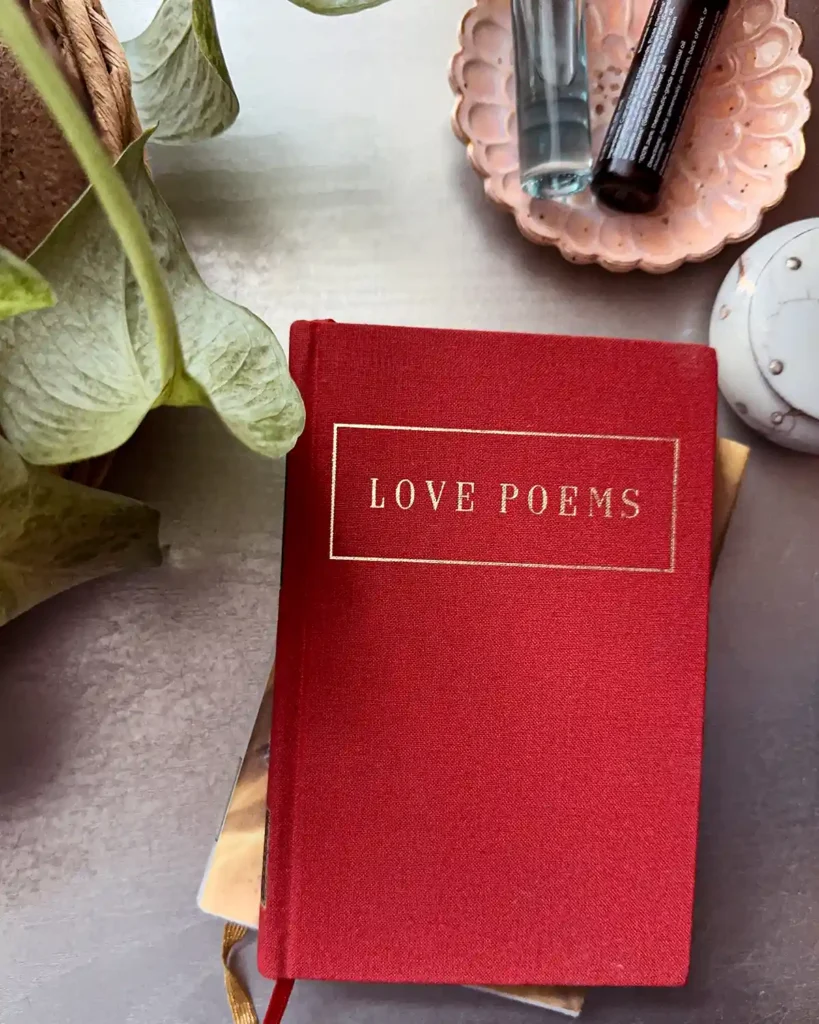 A red book of love poems sitting on a nightstand