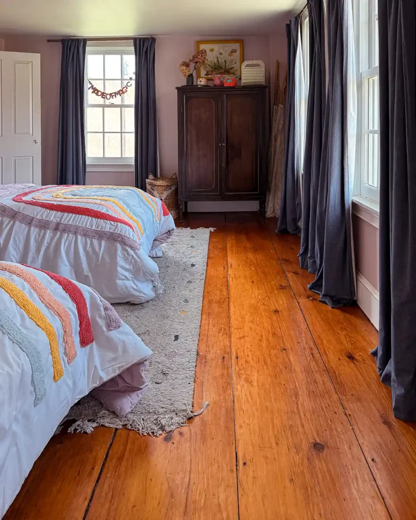 A progress shot of a girls shared bedroom with two twin beds with matching rainbow bedding