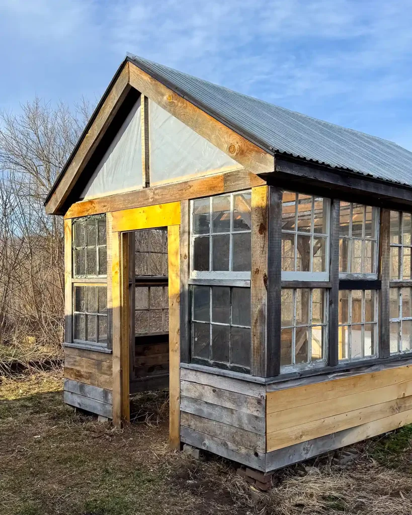 The gable end with entry door to the greenhouse, enclosed with some plastic temporarily to enclose the gable