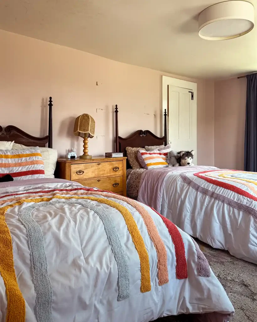 Two vintage twin beds with rainbow bedding in a girls' shared room