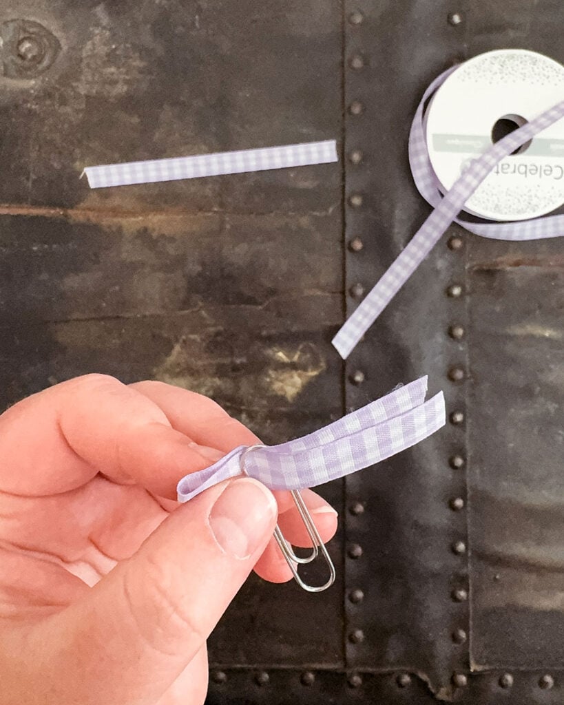 Looping a piece of purple gingham ribbon through the end of the paperclip