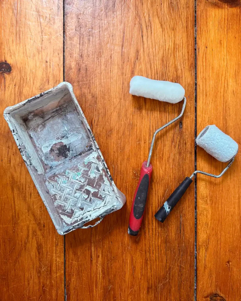 A pair of mini paint rollers and covers along with a mini paint tray