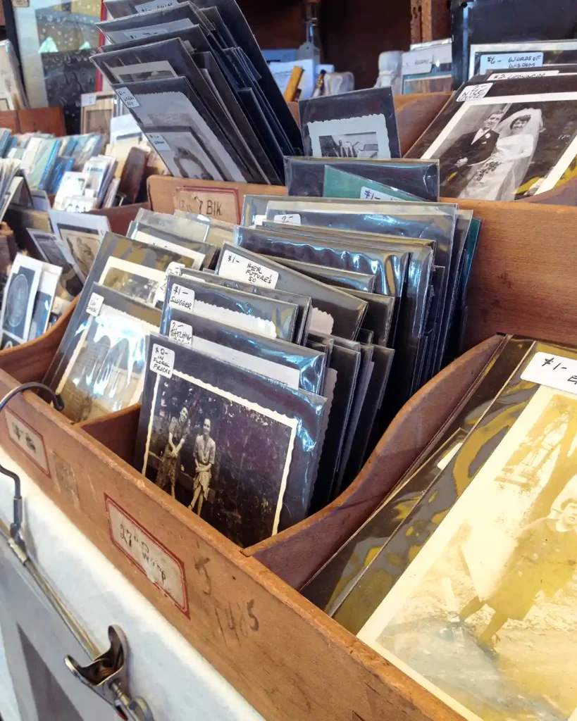 Piles of vintage photographs stacked and curated, marked for sale at a vintage seller's booth at Brimfield