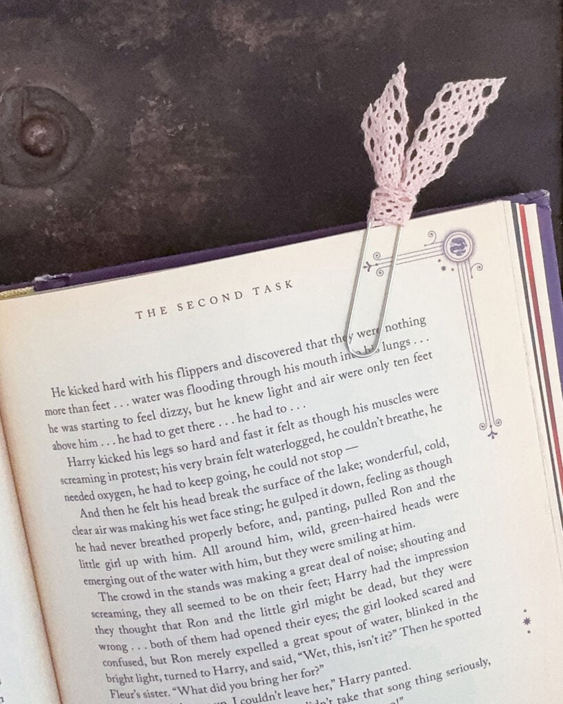 Pink lace ribbon paper clip bookmark clipped to an open Harry Potter book