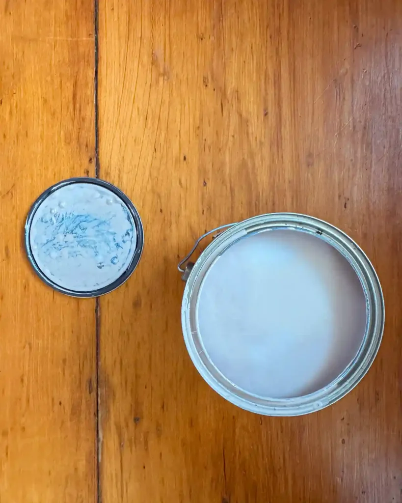 An opened gallon of stain-blocking primer sitting on a wood floor