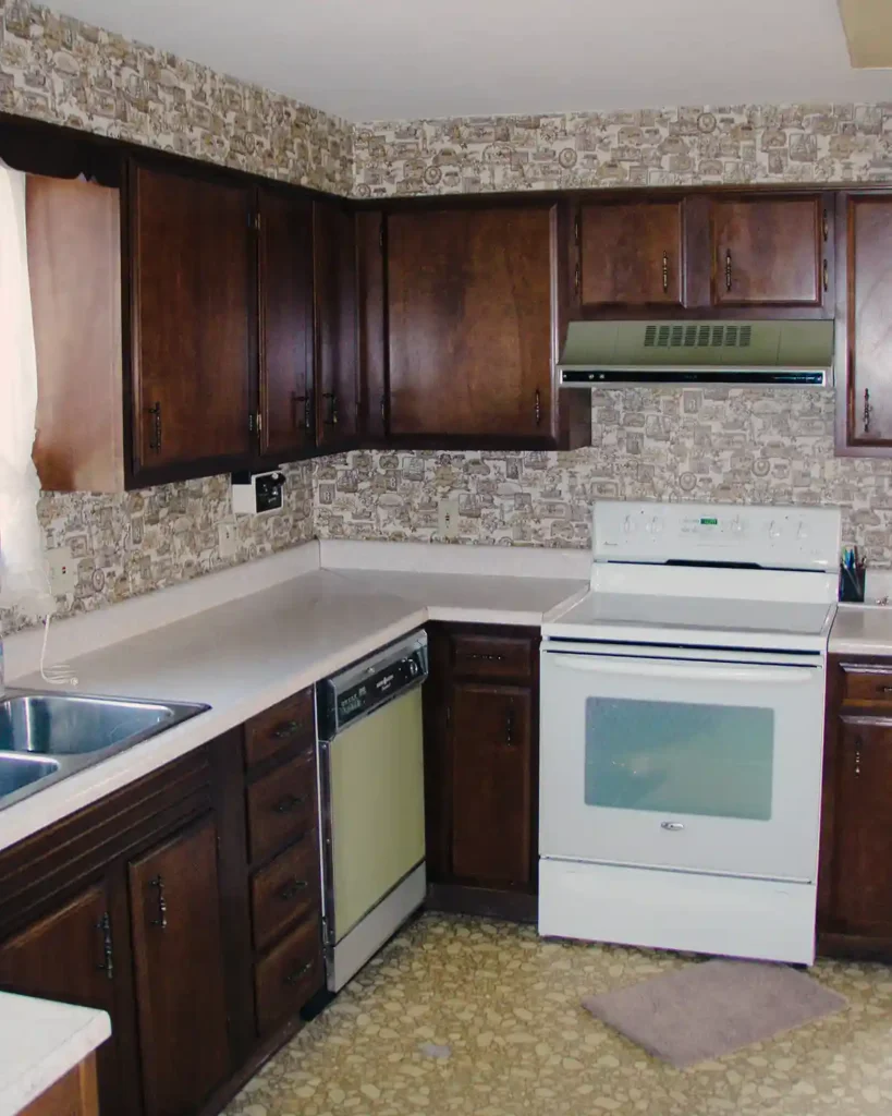A dated kitchen before renovating it complete with paneling, peeling linoleum floors, dark cabinets, white counter top, olive green dishwasher and range hood, white stove, and a textured ceiling