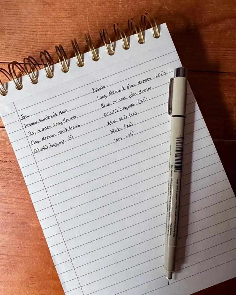 Making a list of back to school kids clothes that the children need on a lined piece of notebook paper before going shopping