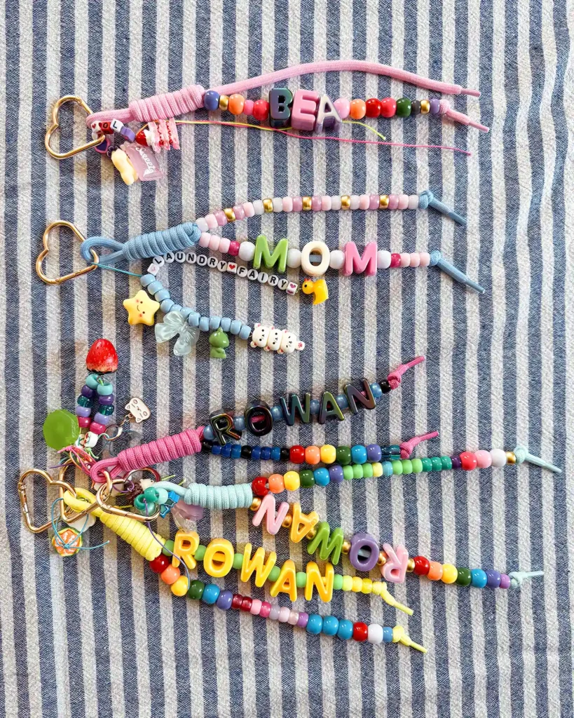 Five chunky letter bead bag charms using heart carabiners, gold heart carabiners, and beaded paracord covered with charms