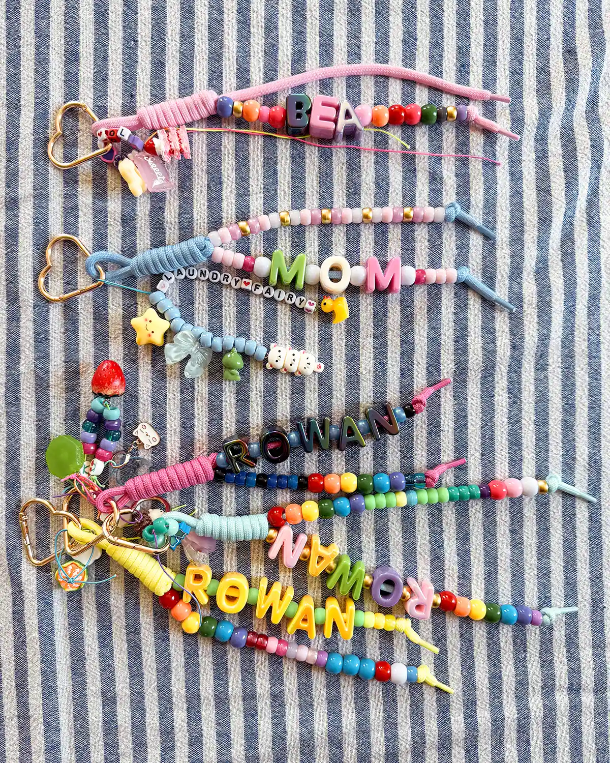 Five chunky letter bead bag charms using heart carabiners, gold heart carabiners, and beaded paracord covered with charms
