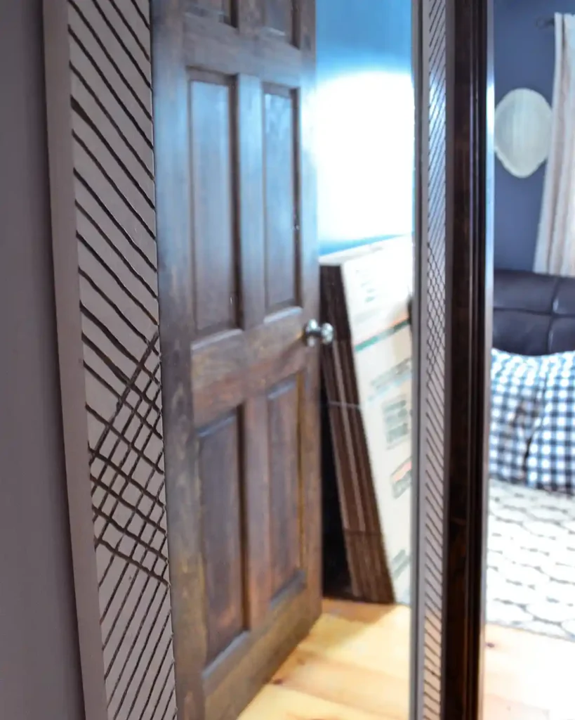 A tall, DIY framed hallway mirror with a routed out geometric design hanging at the end of a hallway