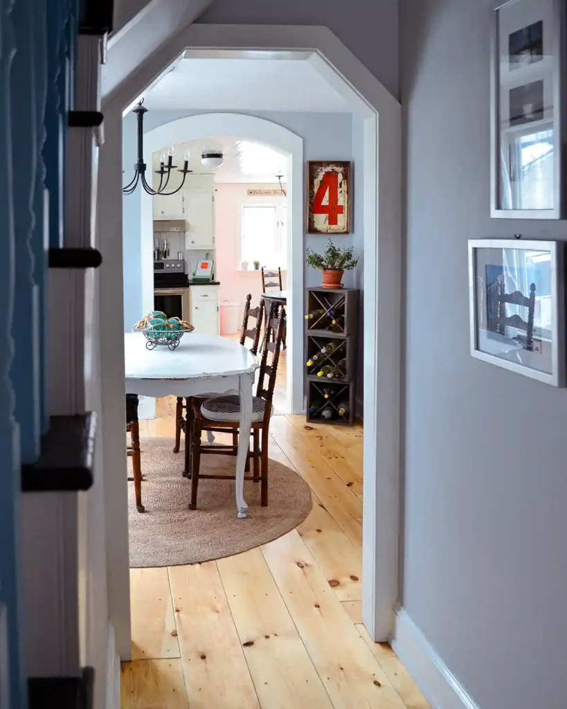 Updated first floor hallway with wide pine floors and grey walls looking into a dining room