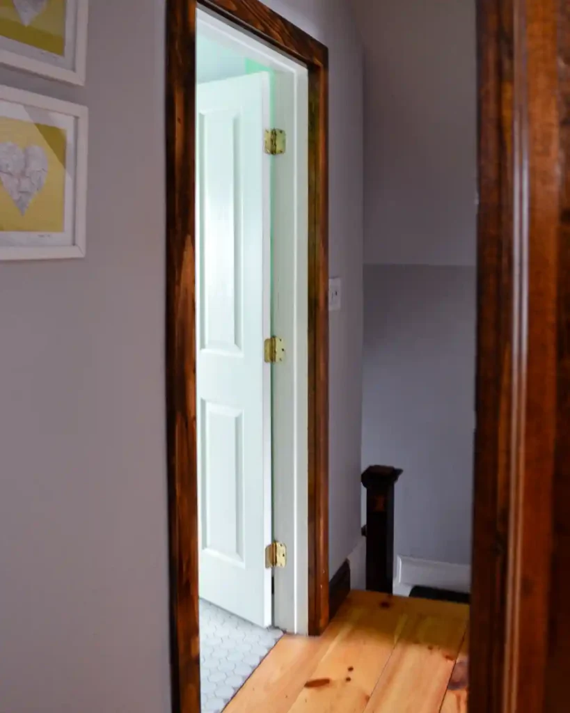 View down a hallway to the top of a staircase with a door open to a bathroom