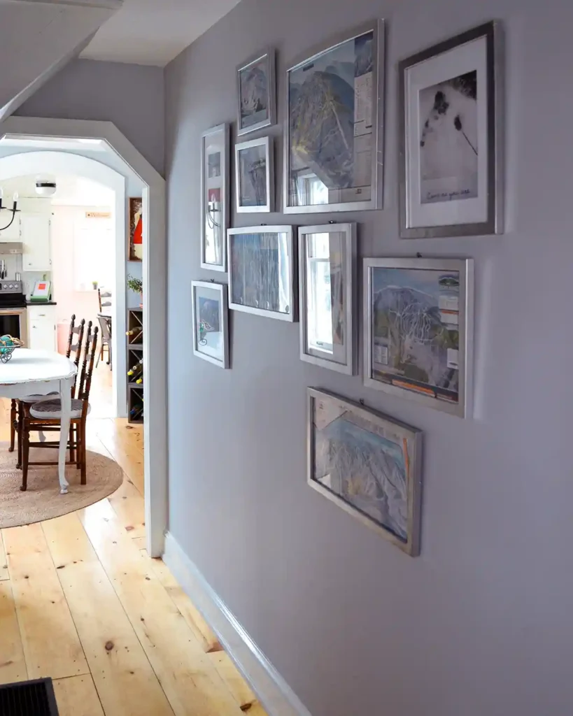 A gallery wall of framed ski maps and skiing pictures in silver frames hang in a first floor hallway