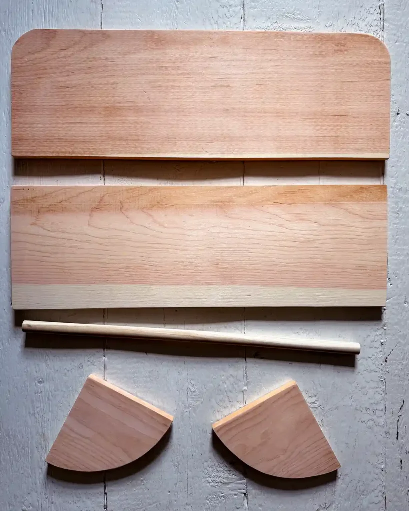 All the wooden parts to assemble a DIY wooden clothes rack to hang on the wall; includes shelf board, backer board, shelf brackets, and wooden dowel