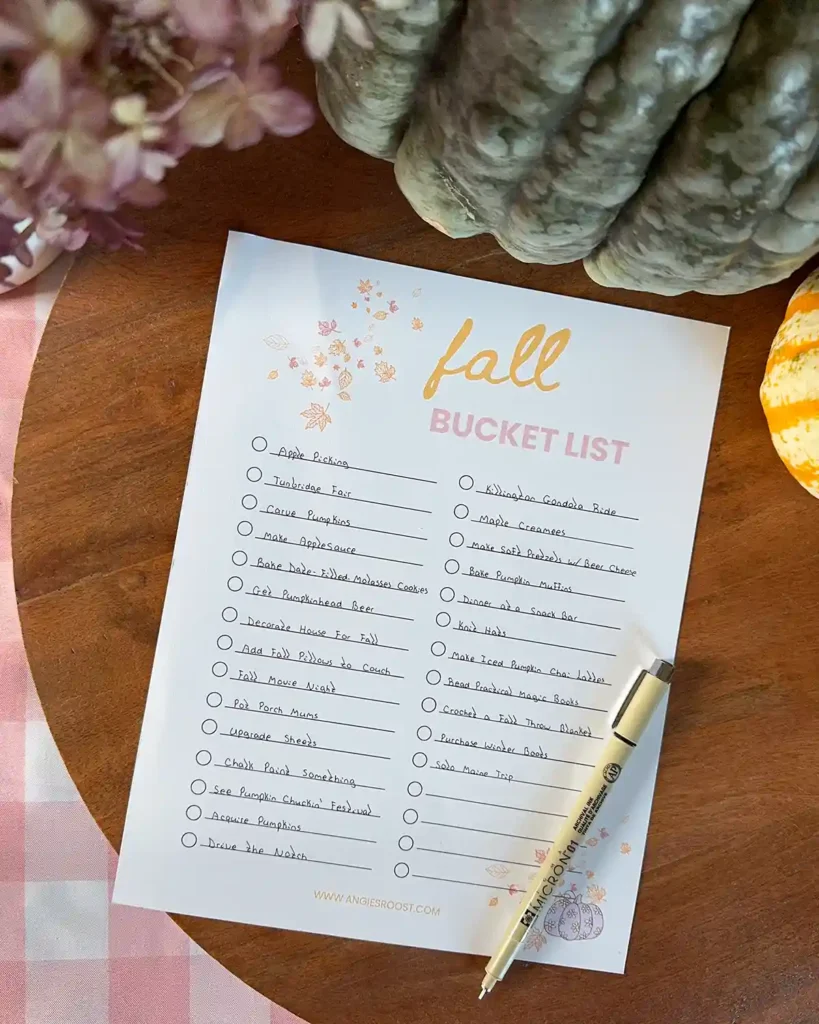 Making a family oriented fall bucket list using a printable; paper list sitting on a wooden tray with a pen and some pumpkins
