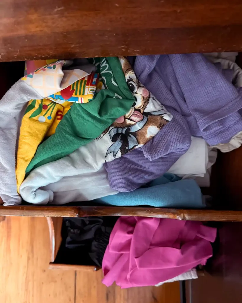 A couple of overstuffed, wooden drawers filled with kids clothes in need of decluttering and organizing
