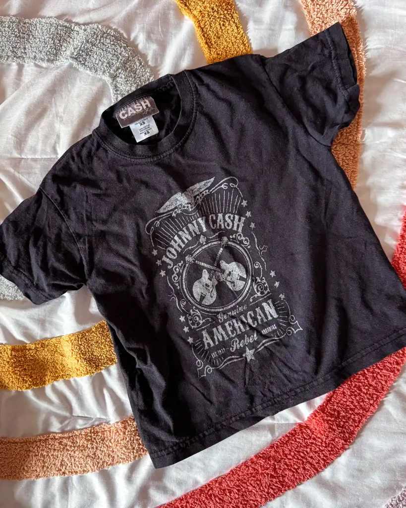 A toddler-sized, black Johnny Cash t-shirt laid out on a bed that's become sentimental to the kids